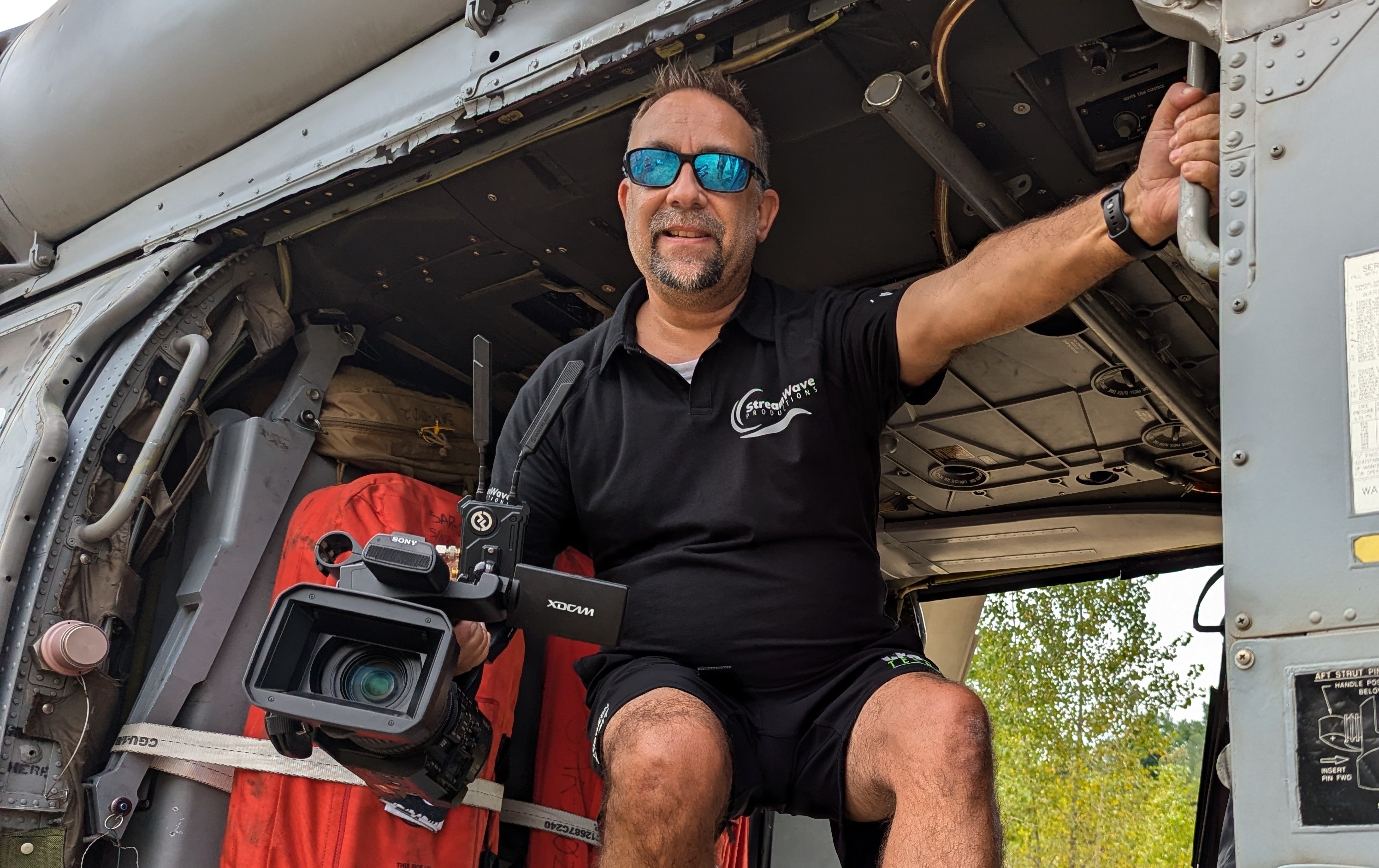 Mark Britton holding a Sony XDCAM camera inside a helicopter